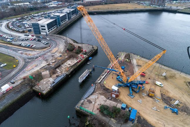 First precast concrete unit is manoeuvred into position by a 1,000 tonne crane