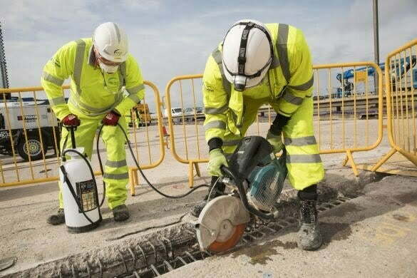 Two construction workers drilling into the ground