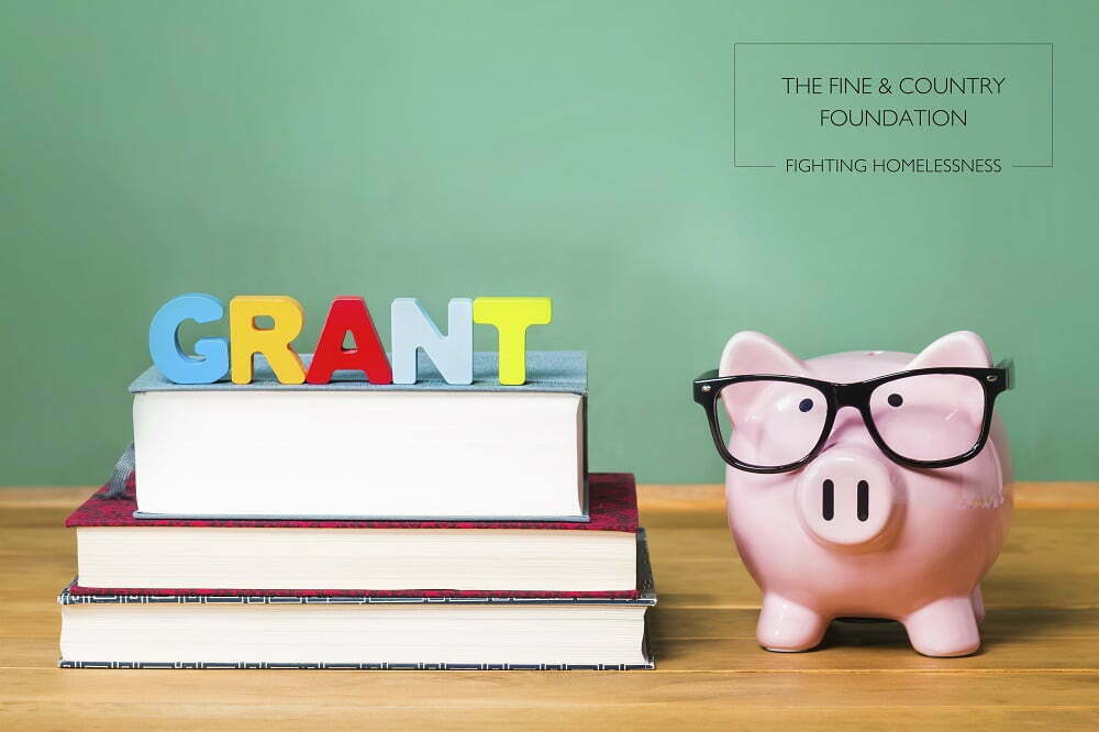 Educational grant theme with pink piggy bank on top of books with chalkboard in the background as concept image of the costs of education