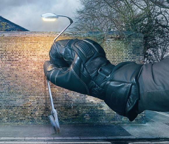 A man bending a street lamp with his motor bike glove