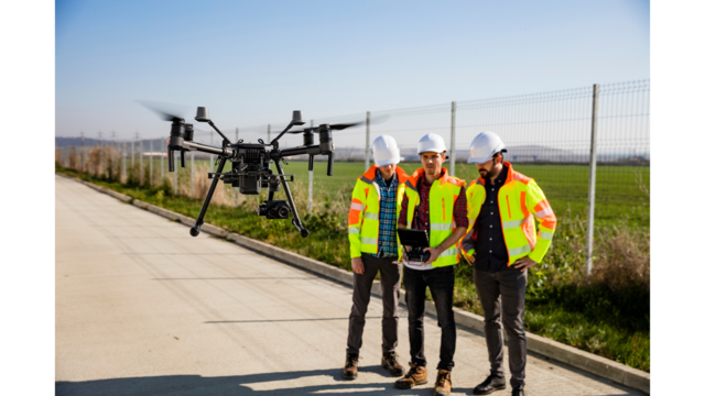 Three construction workers using a drone