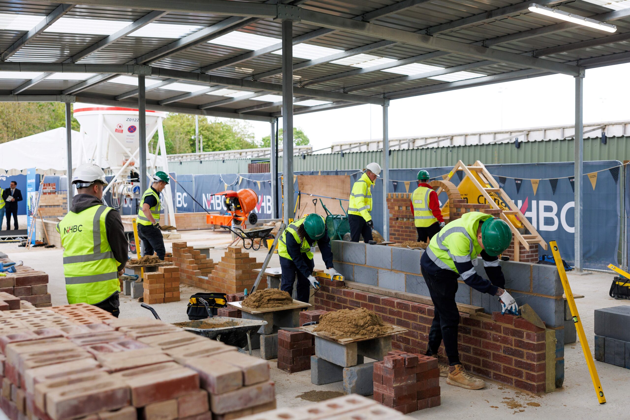 Planning has been approved for a new multi-skill apprenticeship training hub in the town of Northstowe in Cambridgeshire, which will supercharge house-building training and help tackle the construction skills shortage head-on. The NHBC Training Hub, Northstowe, is part of a planned UK-wide network of 12 facilities backed by a £100 million investment from the National House Building Council (NHBC), the UK’s leading provider of new home warranties and insurance. Together, the hubs will train 3,000 new apprentices every year in the most needed trades, with the multi-skill hub at Northstowe set to train 200 per year. The new facility will be delivered in partnership and built by top 10 housebuilder Keepmoat, with land and support provided by Homes England, the Government's housing and regeneration agency. Located on Rampton Road, the hub forms a vital part of NHBC’s commitment to developing a high-quality, skilled construction workforce to support UK housebuilders in meeting the Government’s target of delivering 1.5 million new homes this Parliament. The initiative comes at a critical time, with industry forecasts indicating the UK construction industry needs to recruit an extra 251,500 workers by 2028 to meet demand. Expected to open in early 2026, the NHBC Training Hub, Northstowe, will be two-thirds the size of a football pitch. It will deliver skilled, site-ready tradespeople at pace and scale, providing a significant workforce boost to support housebuilding across the region. Initially, the NHBC multi-skill training hub will focus on delivering apprenticeships in essential trades including bricklaying, groundworks and site carpentry. These will make up around 80% of its use. The remaining capacity will support a range of related activities, including upskilling the existing house-building workforce, traineeships, skills bootcamps, specialist trade masterclasses and sessions for career changers, specialist groups and school students. These activities will showcase the wide-ranging opportunities within the housebuilding sector. The facility is designed to be flexible and responsive to local needs and evolving regulatory requirements, ensuring a consistent flow of qualified tradespeople needed to build high quality homes in the area. NHBC’s innovative training model means 200 new apprentices each year from diverse backgrounds will benefit from immersive, hands-on learning in real site conditions from day one at the NHBC Training Hub, Northstowe. Results from NHBC’s existing training hubs show apprentices are completing this industry-leading and tailored training in as little as 14 months, with many achieving distinctions. That’s nearly twice as fast as traditional education routes, which can take up to 30 months. Commenting on NHBC’s Training Hubs, Jacqui Smith, Minister for Skills, said: "This government is committed to creating opportunities for people across the country to access well-paid jobs in vital sectors like construction and NHBC's excellent new training hubs are helping to deliver exactly that. “Their innovative model will prepare apprentices at the pace and scale we need to tackle the construction skills shortage and deliver our ambitious target of 1.5 million new homes this Parliament. “These hubs will equip local people with high-quality skills and rewarding careers, whilst building the communities of the future and supporting our economic growth mission." Commenting on the approval of the new NHBC Training Hub, Northstowe, Roger Morton, Director of Business Change at NHBC, said: "We’re not just training apprentices, we’re raising the standard for the whole house-building industry. Our new NHBC multi-skill hub at Northstowe, along with our 11 others planned across the UK, will deliver quality training at scale in a way the industry has never seen before. Apprentices learn in real-site conditions from day one, gaining hands-on experience in the same conditions they’ll face in the job. It means faster progress, stronger results and most importantly, skilled, site-ready tradespeople. "The industry is under real pressure to build more homes, build them well and find the skilled people to do it. That’s why the Chancellor’s recent Budget announcement is so significant. Although we await the full details, making apprenticeship training free for under-25s taken on by small and medium-sized builders removes one of the biggest barriers to hiring new talent. Cost, time and uncertainty have held many builders back and now those barriers could be about to come down. "Combined with NHBC’s £100 million investment in 12 multi-skill hubs across the UK, training 3,000 new apprentices every year, this is a huge opportunity for smaller builders who are the backbone of our industry. With free training and access to NHBC’s real-site hubs, where apprentices reach top industry standards in as little as 14 to 18 months, builders can take on new recruits with confidence. Together, we can tackle the skills shortage and deliver the homes the UK urgently needs." Alison Crofton, Chief Property Officer at Homes England, added: “As the government’s housing and regeneration Agency, supporting NHBC’s multi-skill training hubs takes us a step closer to delivering on the government’s mission to build 1.5 million homes this parliament. The hubs are a brilliant opportunity to bridge the gap between construction skills development and housing delivery, bringing much-needed new talent into the industry at a pivotal time for housebuilding. “As we continue to deliver phases two and three of Northstowe, the NHBC Training Hub will fast-track hundreds of apprentices into high-quality, site-ready roles, enabling meaningful training for local people and supporting a skilled workforce that can continue to build the future of Cambridgeshire. “We’re proud to provide the land and support NHBC and Keepmoat on the programme, which will not only accelerate progress at Northstowe, but also set a benchmark for large-scale, sustainable communities across the country.” Tim Wray, Group Land and Partnerships Director at Keepmoat, added: “We’re thrilled to be working closely in partnership with the NHBC and Homes England to deliver this multi-skills accelerated apprenticeship hub at Northstowe. “At Keepmoat, we’re committed to building communities and transforming lives. Working with NHBC on initiatives such as this is critical to ensure the future workforce is equipped with the required skills, knowledge and experience to deliver high quality, affordable homes and sustainable communities. “The initiative will also work to attract and nurture new talent into the sector, addressing the skills shortage and increasing awareness of the rewarding career opportunities available in construction.” NHBC is currently evaluating additional locations across the UK for its new multi-skill training hubs. These hubs form a key part of the Home Builders Federation (HBF) Sector Skills Plan. For more information, visit Apprenticeships | NHBC.