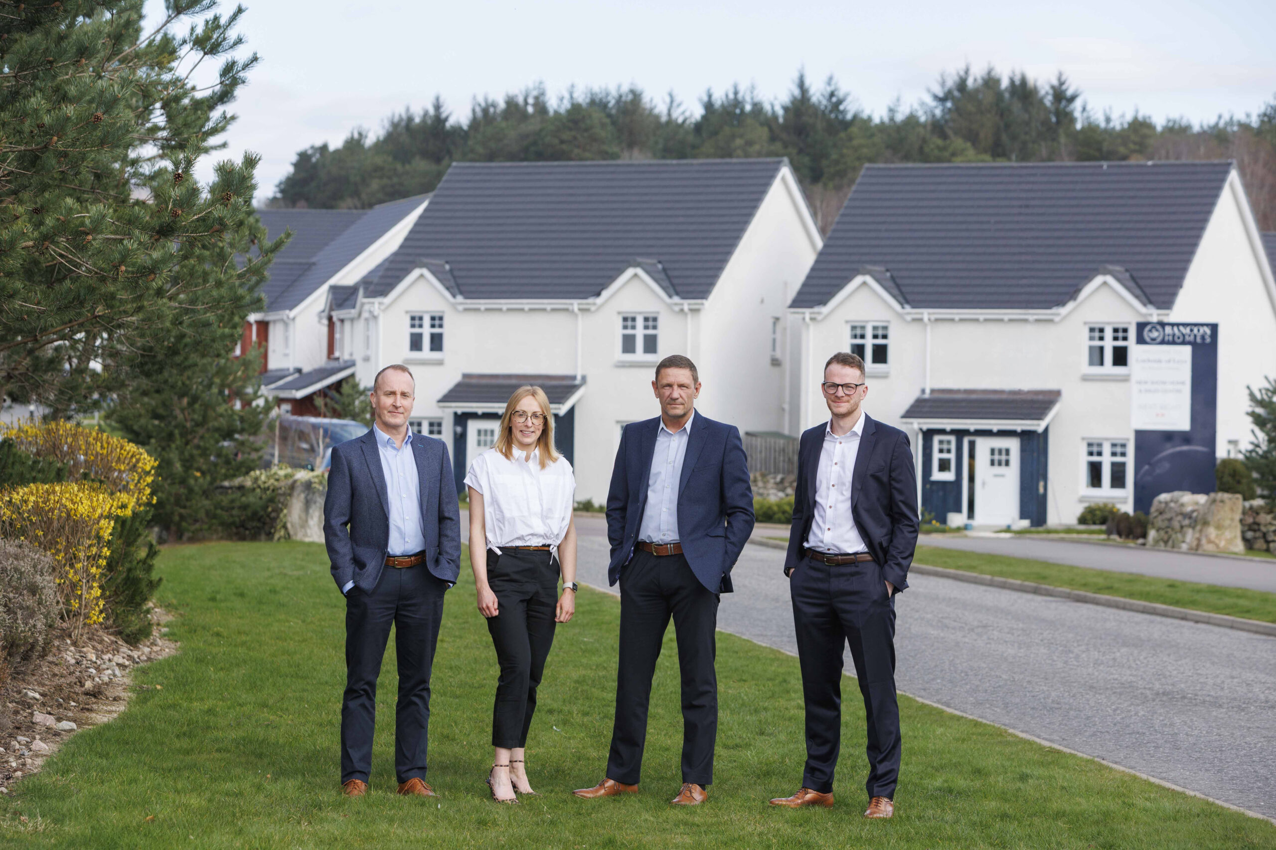Three men and a woman stood outside on a grass verge of the Bacon Group Homes estate in Scotland