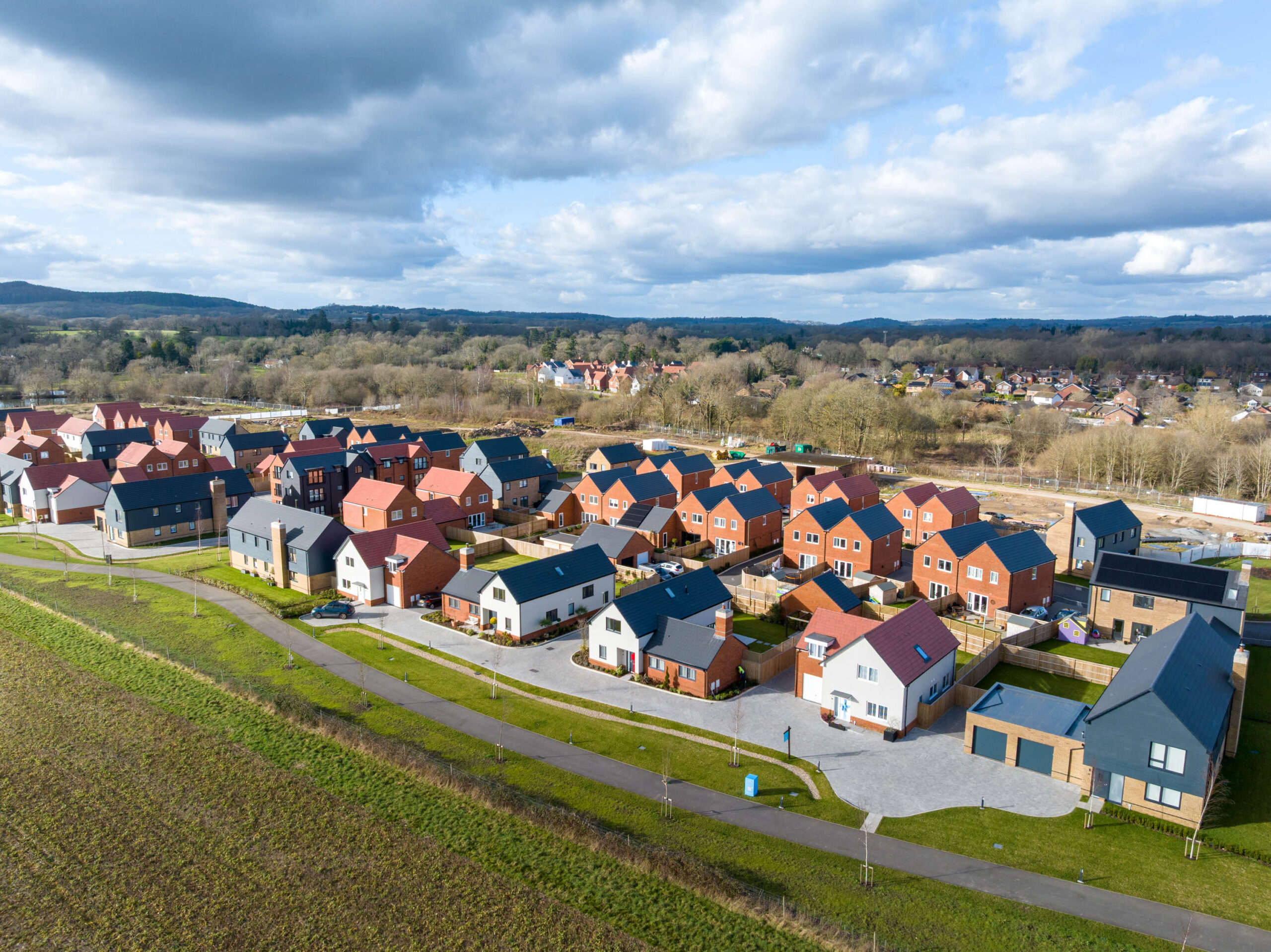 Birds-eye-view of a housing estate, surrounded greenland and urban greenland, with a further housing estate in the distance