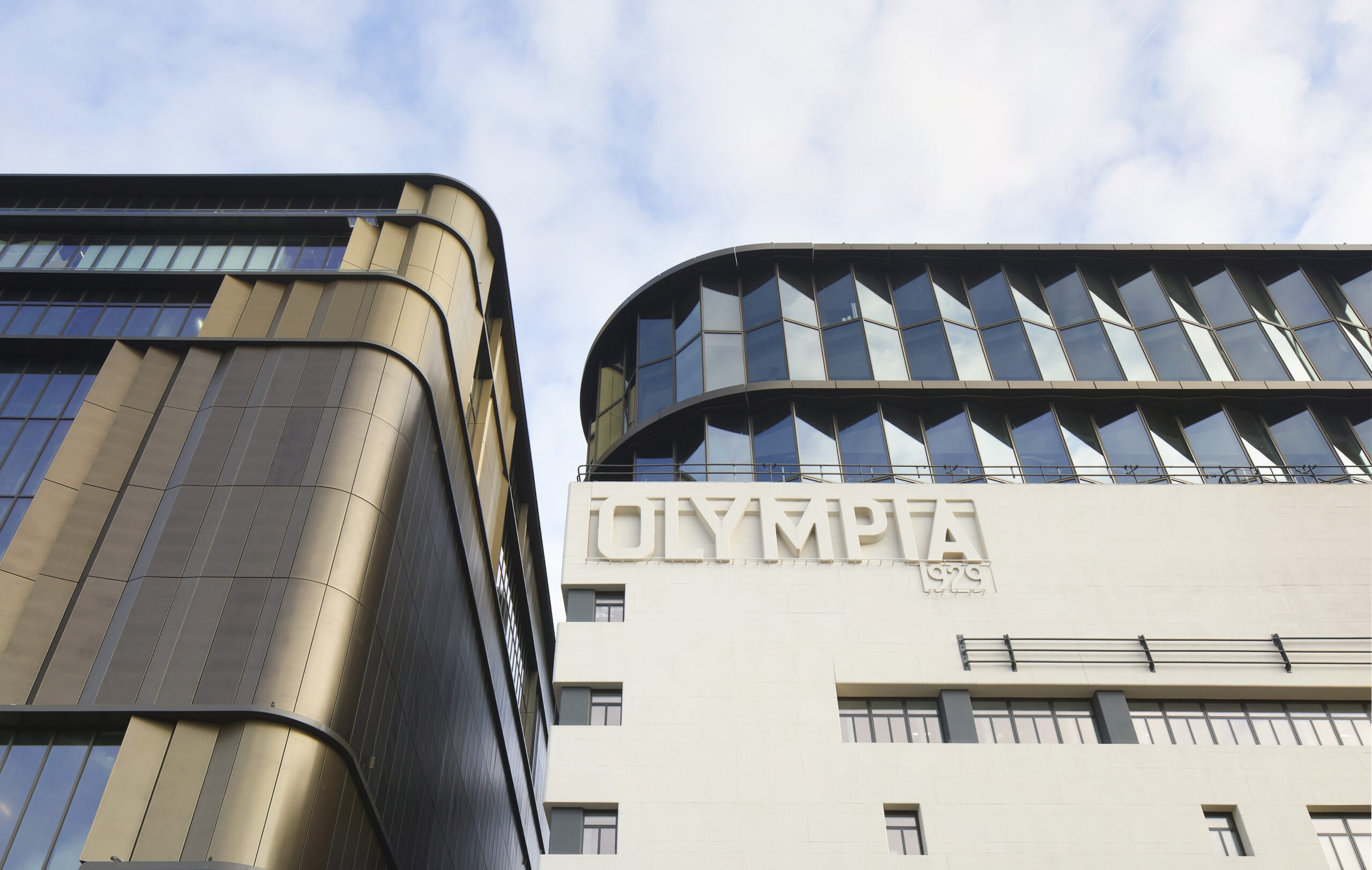 A close up of Olympia Theatre Heatherwick building stood next to a brown building