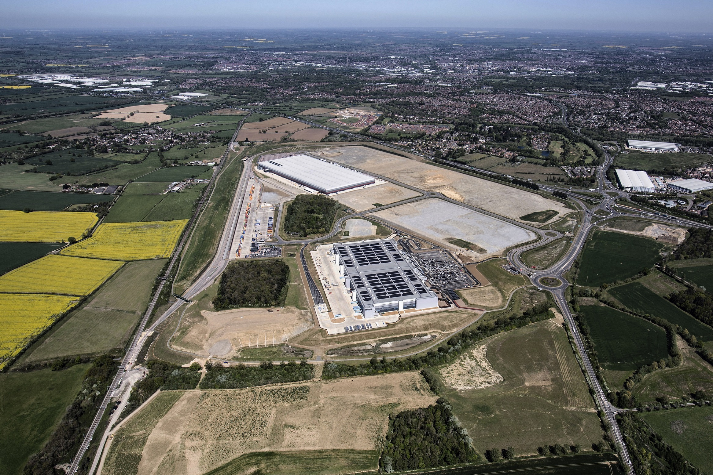 A birds-eye-view of private land and the Logistics Park Northampton with houses and buildings in the distance