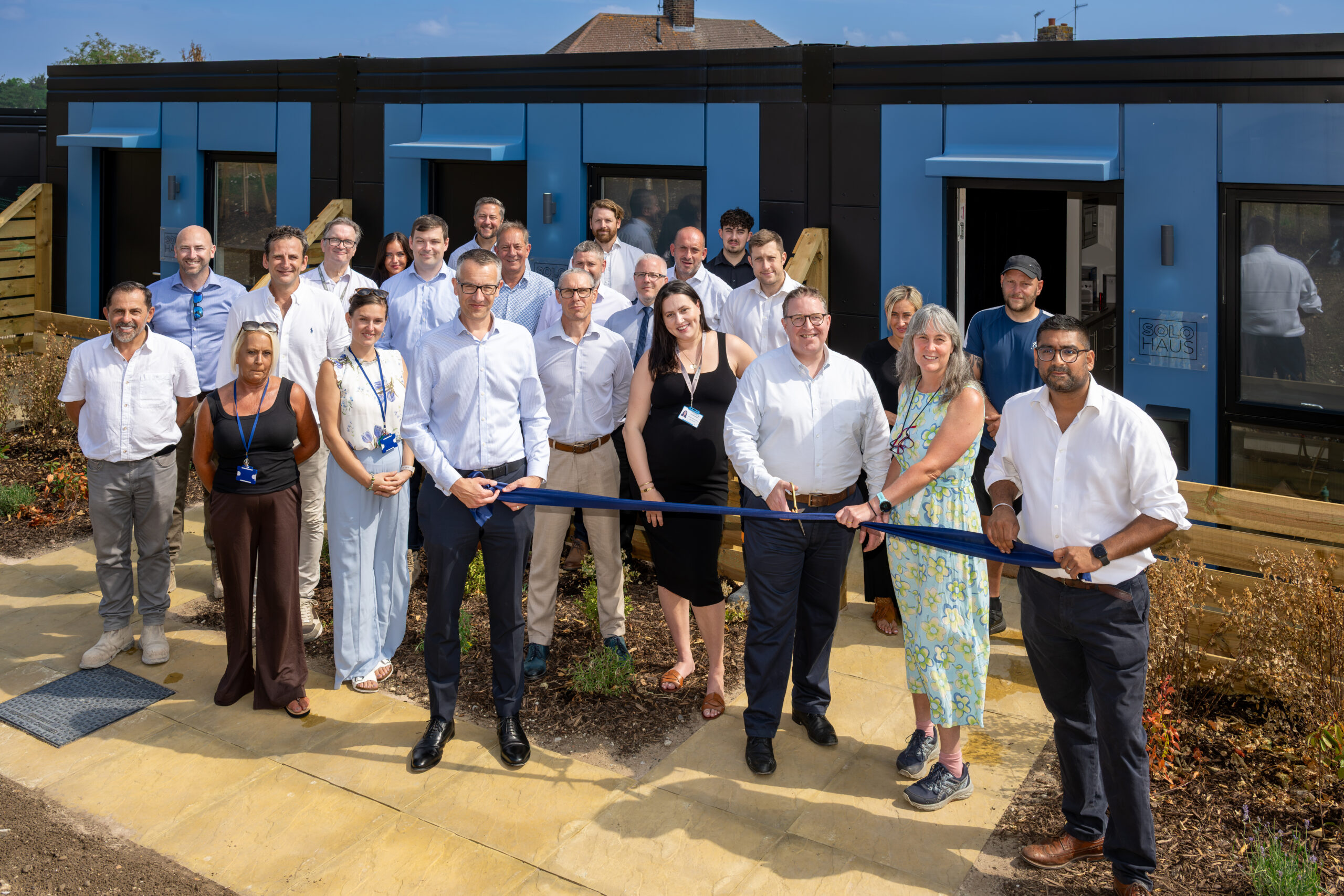 A group of 24 people who are members of staff for either The Hill Group, wearing formal clothing at the opening of the eight homes for Gravesham's Homeless