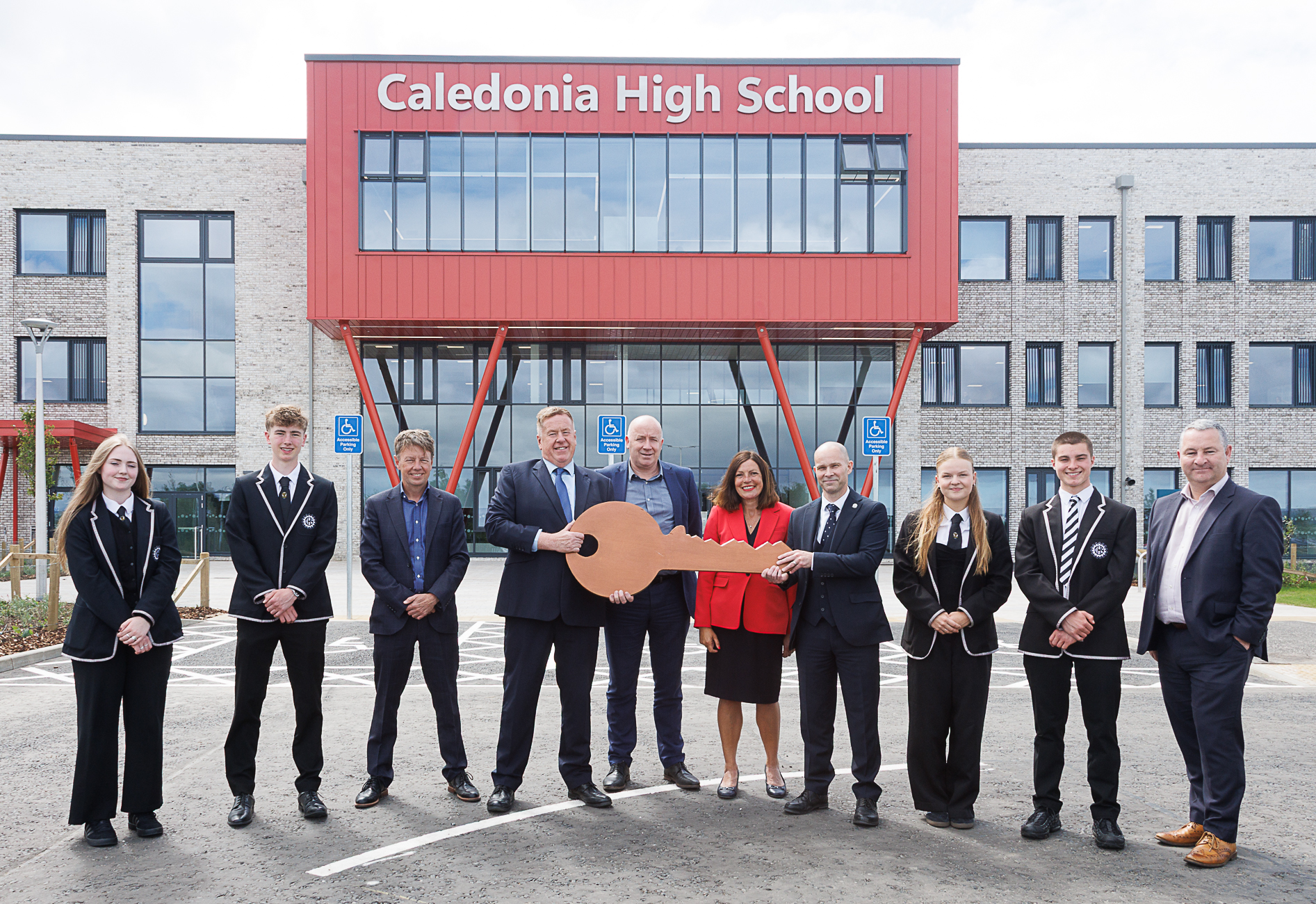 eight people stood outside the Caledonia High School, with a large, cardboard cut out of a key as it is handed over to Fyfe Council