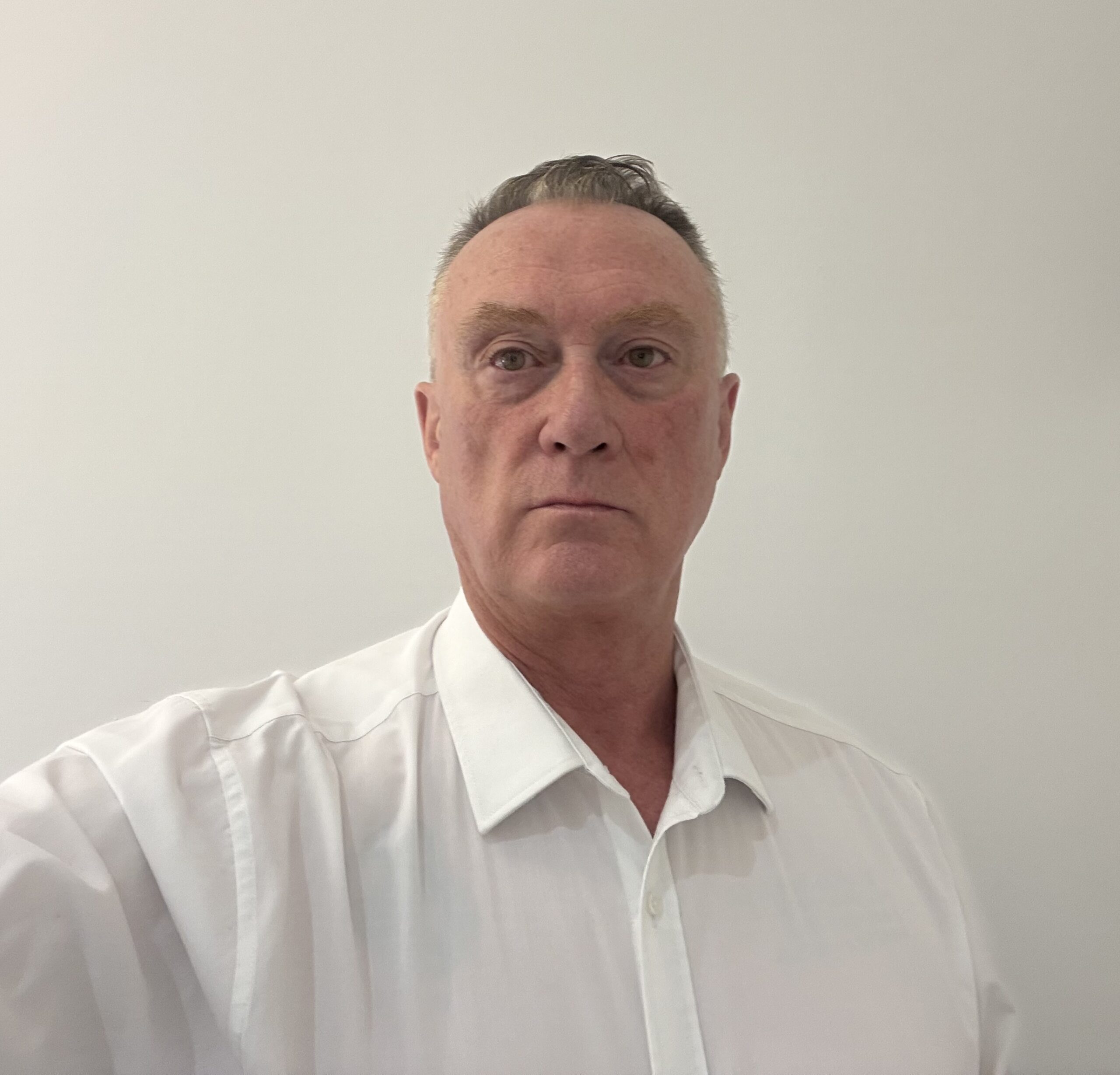 A selfie of Lyndon Johnson, Managing Director of Huws Gray, wearing a white shirt amongst a white background