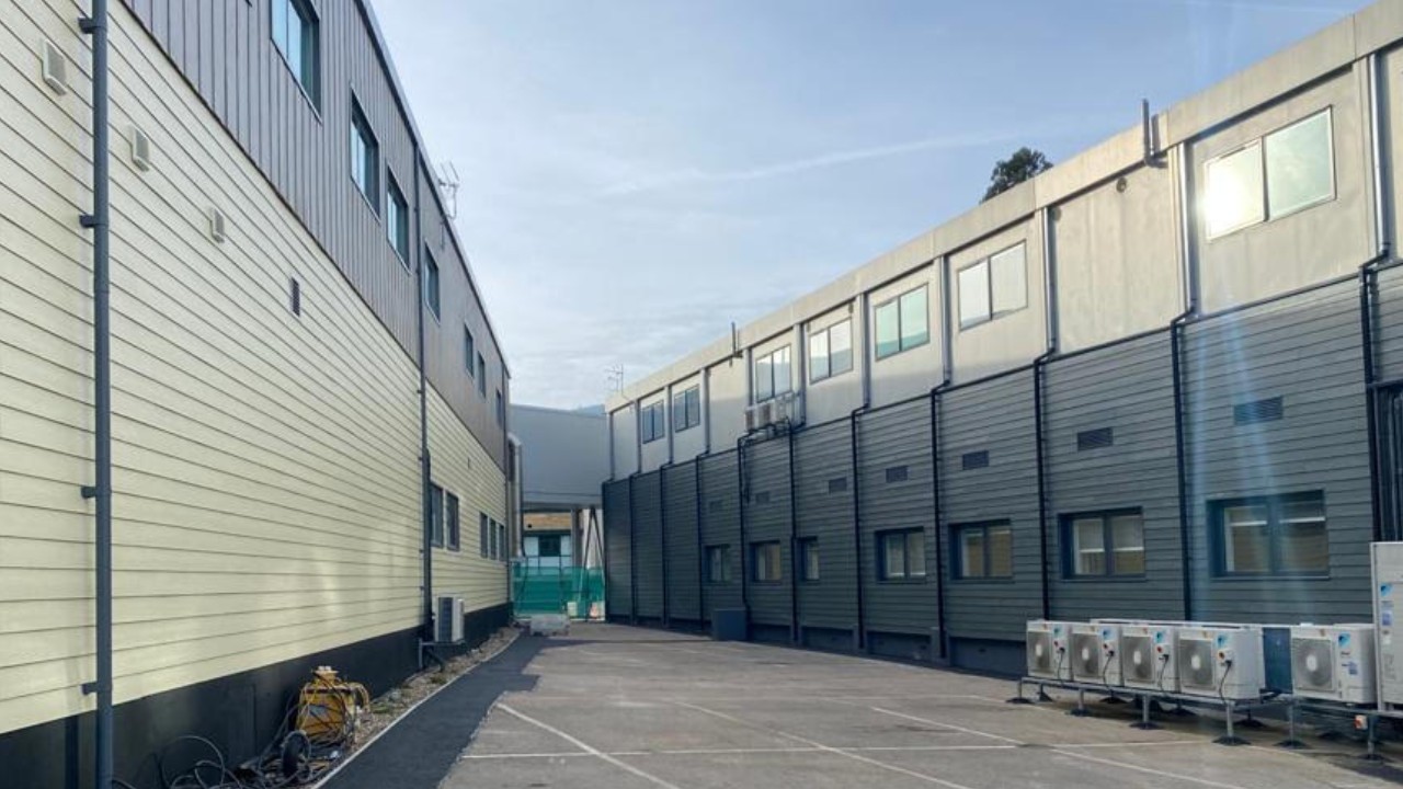 The back of two separate buildings that are part of the Princess Alexandra Hospital, separated by a paved alleyway
