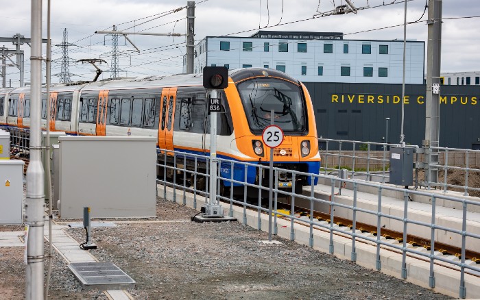 An orange train on a train track entering the Riverside Station