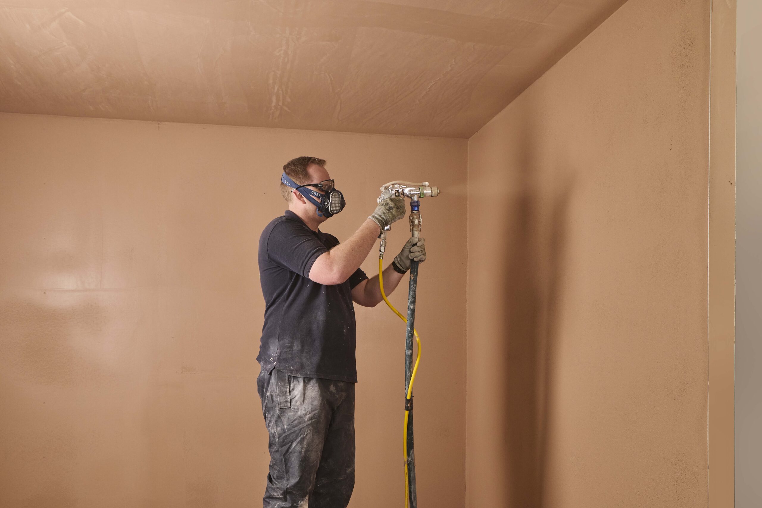 A male plasterer stood in a plastered room