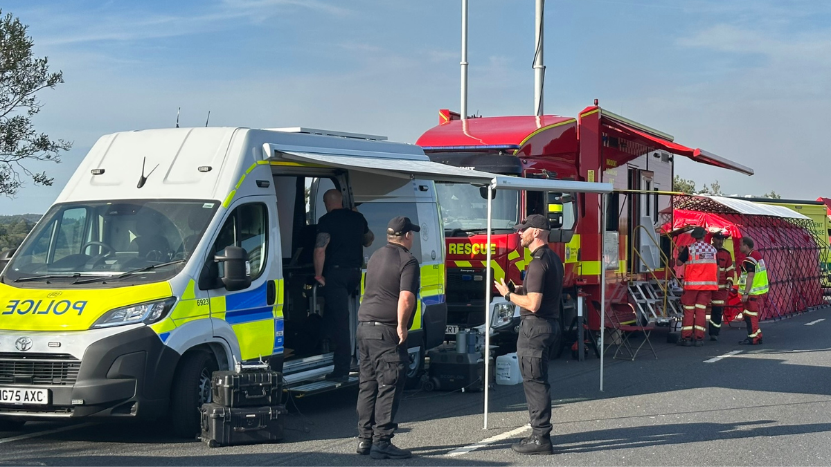 A31 heathland fire - teams on site stood talking in front of a police car and fire station