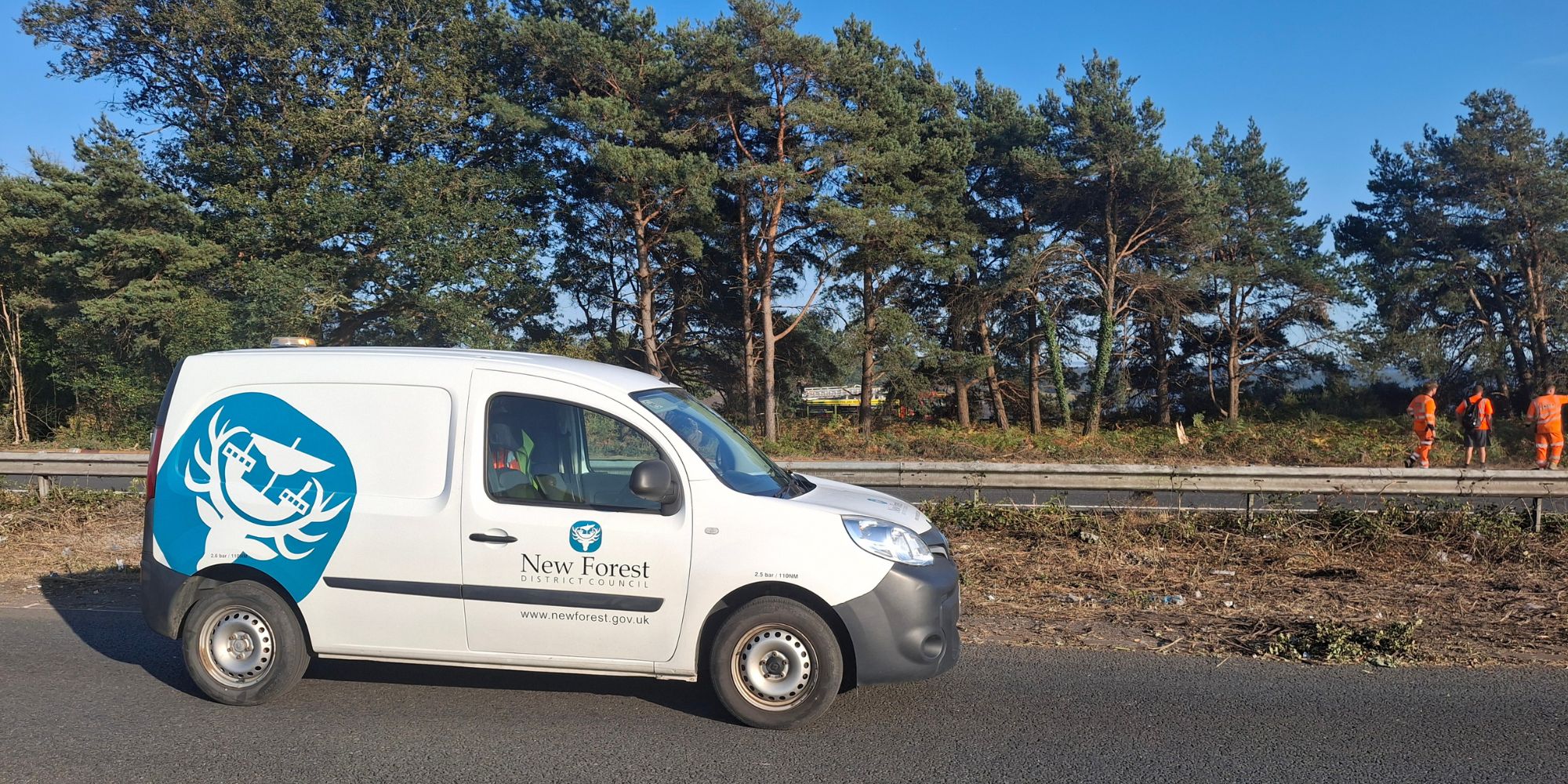 home-staging_01 An image of a parked 'New Forest' van with three workmen in orange high-vis clothing with large trees in the distance