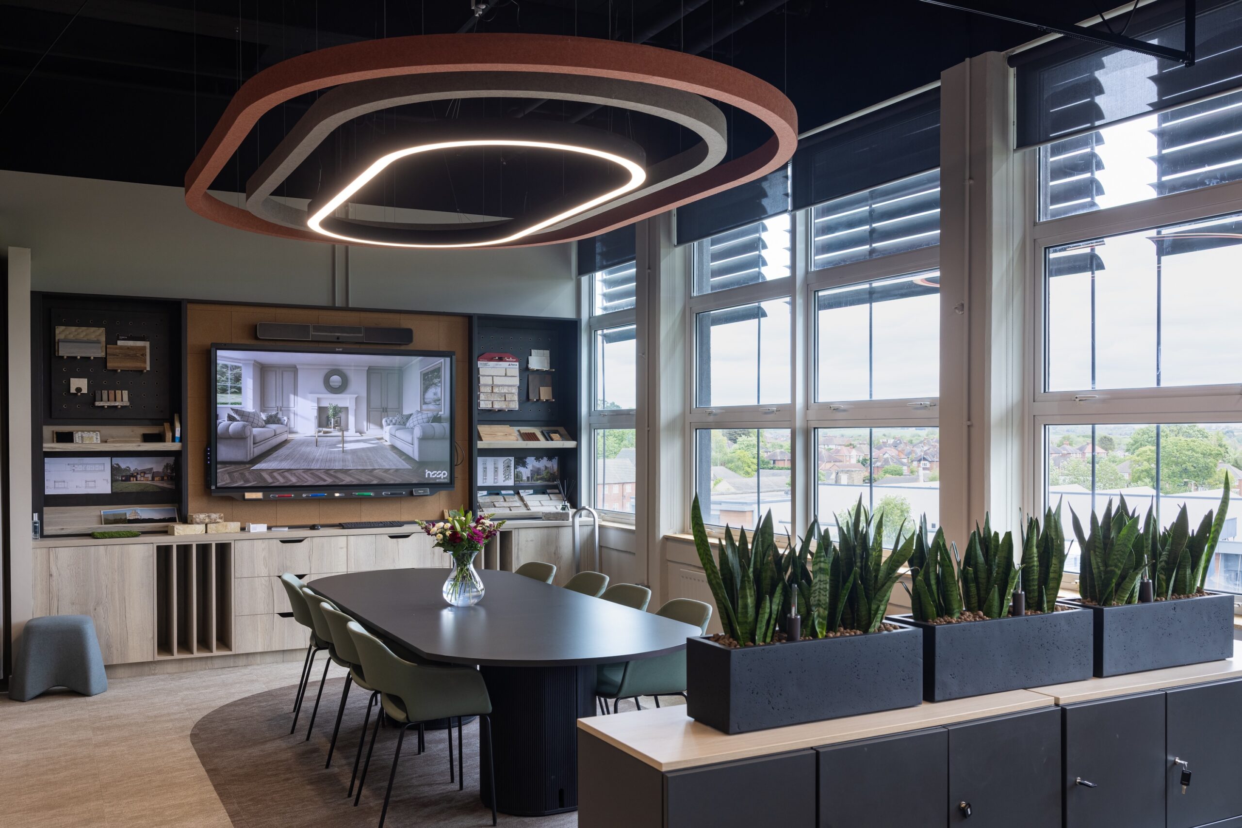 Long shot of HSSP Architect's revamped headquarters office, showing a large light, a table in the middle of the room and a television. Image credit: Osborne Photography