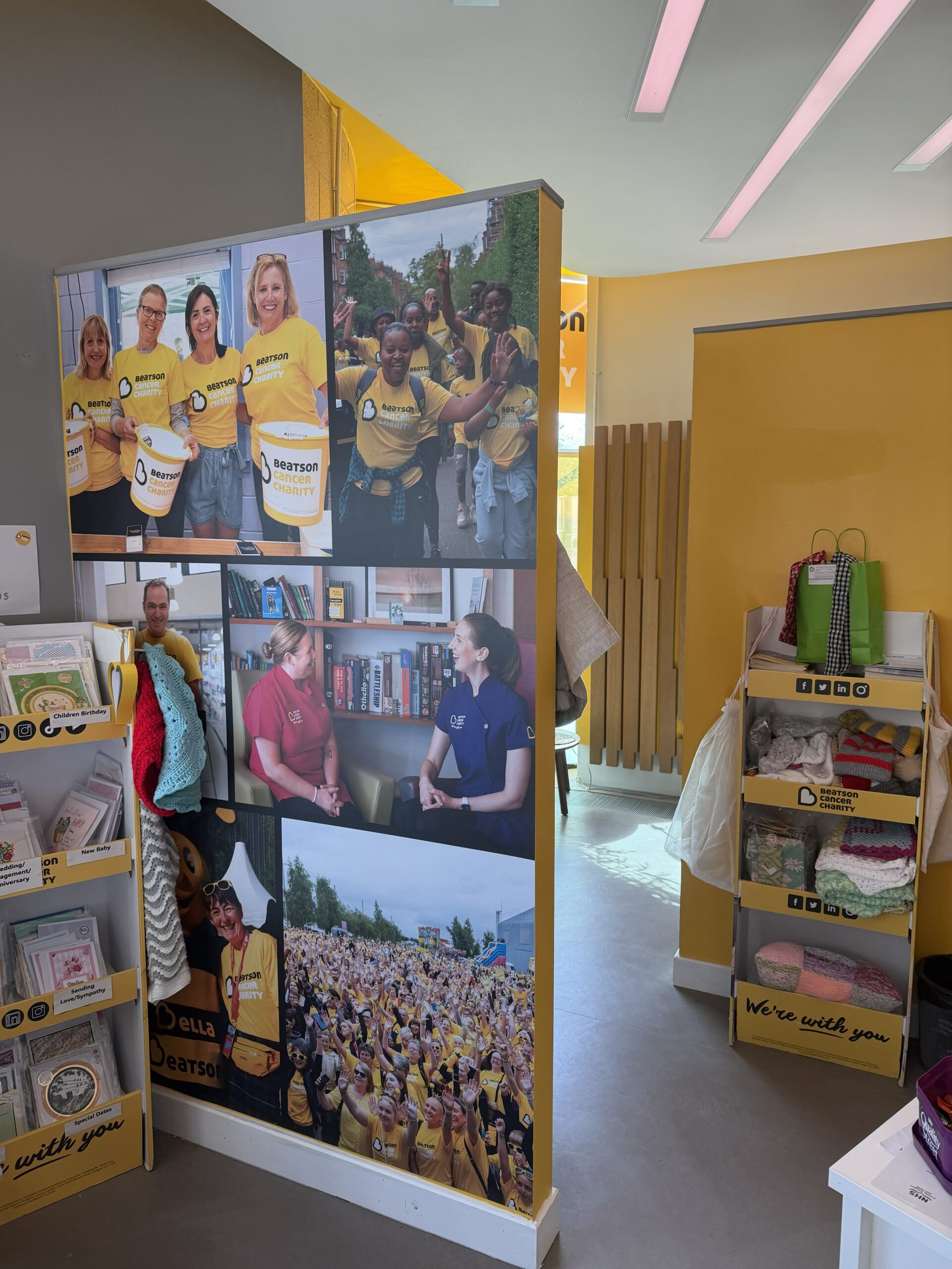 A yellow pop up book shelf and a wall featuring a collage of photos from the Beatson Cancer charity