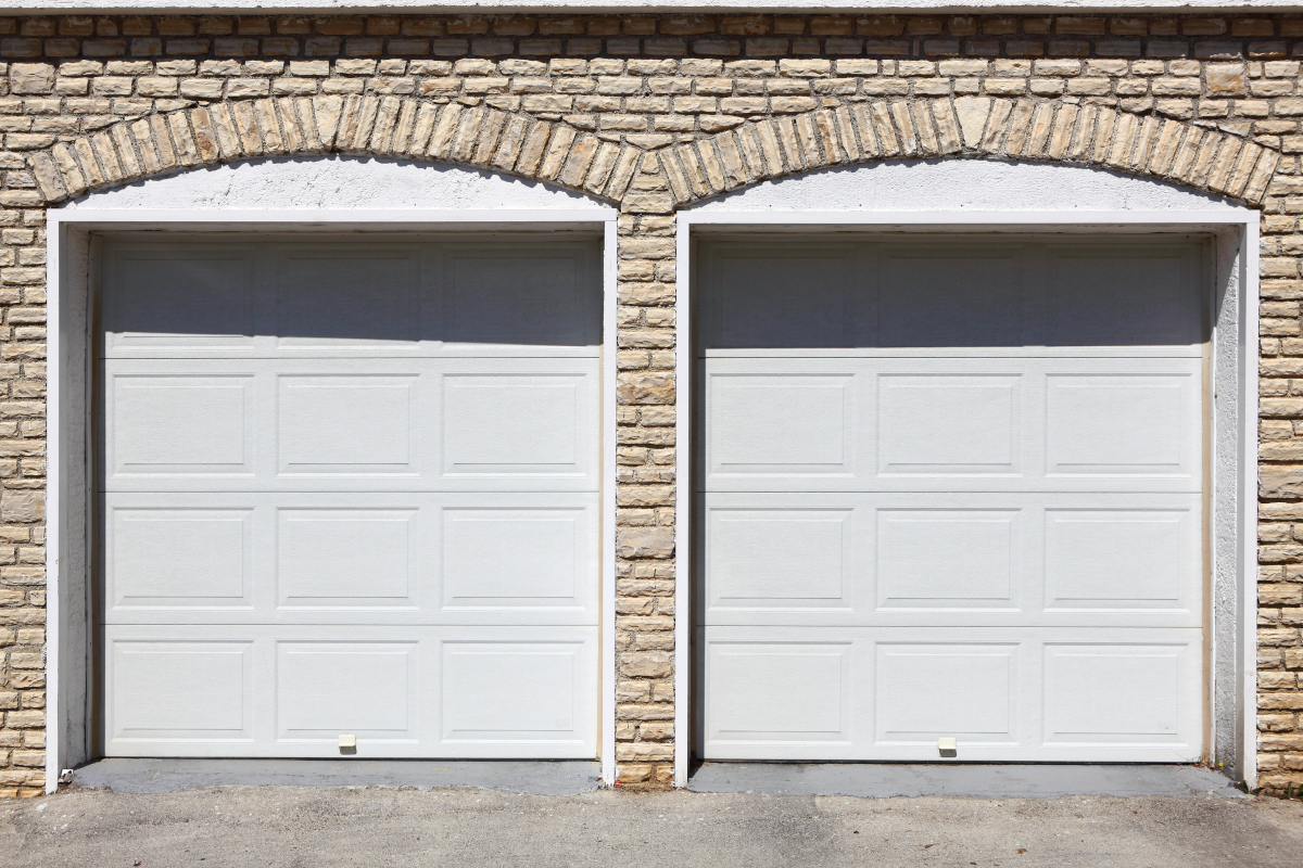 Two white garage doors integrated within a wall.
